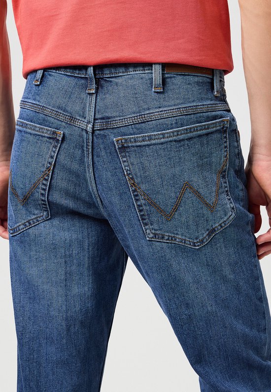 Dichtbij de achterkant van de blauwe spijkerbroek, met geborduurde 'W' op de zakken.