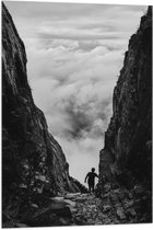 WallClassics - Vlag - Man tussen Rotsen boven Wolken in Zwart-wit - 60x90 cm Foto op Polyester Vlag
