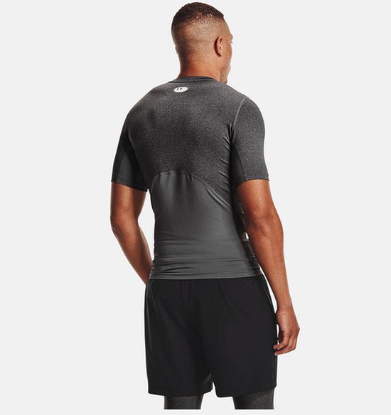 Man met donkergrijs, kort sportshirt met grijze panelen op de romp en rug.