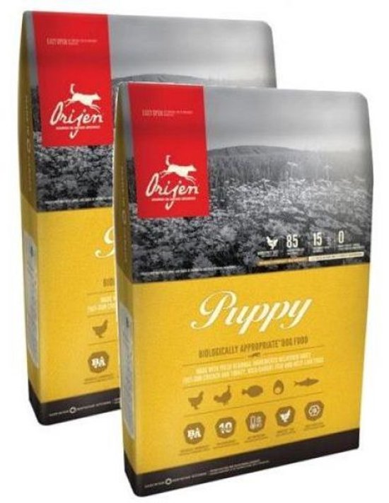 Twee zakken Orijen puppyvoer met een gele voorkant en een afbeelding van Orijen's logo met een rennende hond en de tekst 'Puppy'.