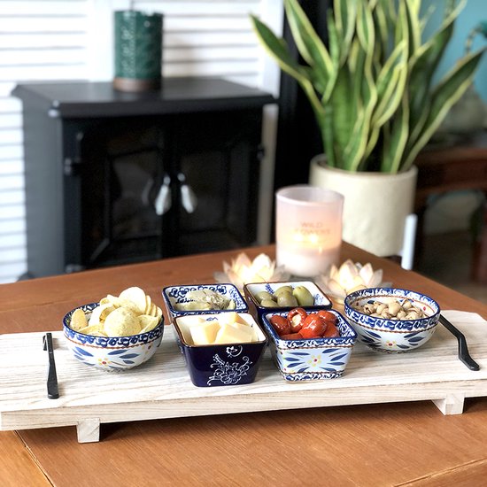 Vijf tapas schaaltjes met blauwe bloemenrand, gevuld met chips, kaas, olijven, pepers en noten.
