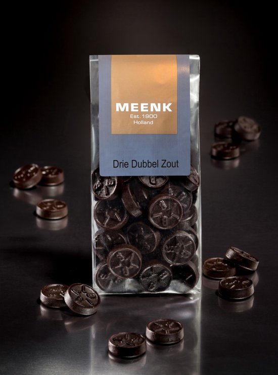 Zakje met Meenk Drie Dubbel Zoute dropjes, donkerbruin, met sterpatroon. Tekst op zakje: MEENK, Est. 1900 Holland, Drie Dubbel Zout.