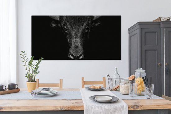 Toile noir et blanc d'un taureau sur fond sombre, au-dessus d'une table à manger.