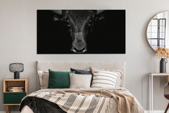 Toile noir et blanc d'une tête de taureau au-dessus d'un lit. La toile remplit le mur.