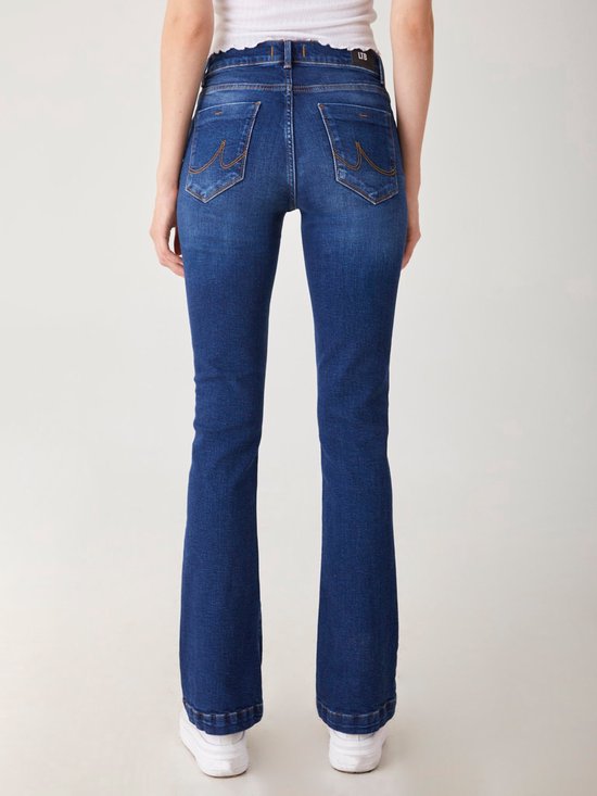 Achterkant van een donkerblauwe flared jeans met LTB logo en witte sneakers.