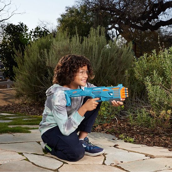 Jongen knielt buiten en houdt een blauwe Nerf Elite Tetrad blaster vast, met oranje darts zichtbaar.