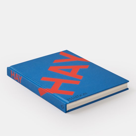 Blauw boek met grote oranje letters "HAY" op de voorkant. "Phaidon" staat onderaan.