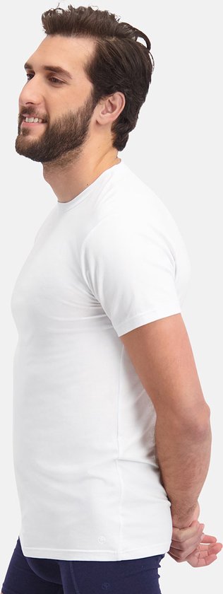 Man met baard, zijkant van een wit T-shirt met ronde hals, handen achter de rug.