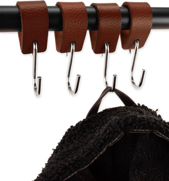 Bruine leren lussen met zilveren en zwarte s-haken, een zwarte jas hangt aan een haak.
