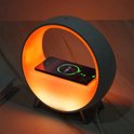 Witte ronde wekker met een heldere oranje gloed en een smartphone die draadloos wordt opgeladen.