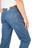 Achterkant van een man in een blauwe spijkerbroek, met Wrangler logo op de bruine leren patch.