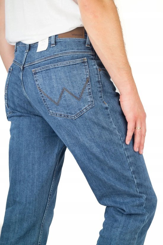 Achterkant van een man in een blauwe spijkerbroek, met Wrangler logo op de bruine leren patch.