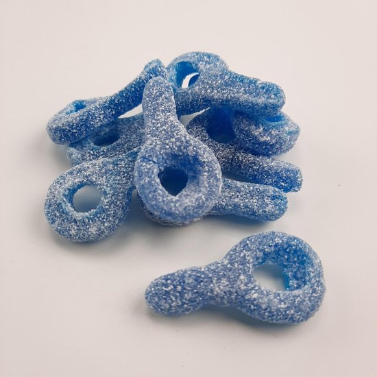 Blauwe, ringvormige zure snoepjes, bedekt met suiker, in een hoopje op witte achtergrond.