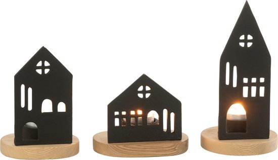 Drie zwarte metalen huisjes op houten basis, met brandende kaarsen. Details van ramen en deuren zichtbaar.