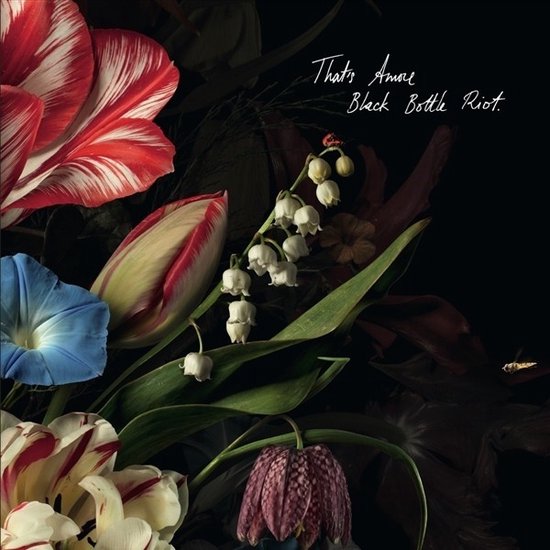 Bloemenarrangement met rode gestreepte tulpen, lelietjes-van-dalen en een blauwe ochtendglorie. Tekst: That's Amore Black Bottle Riot.