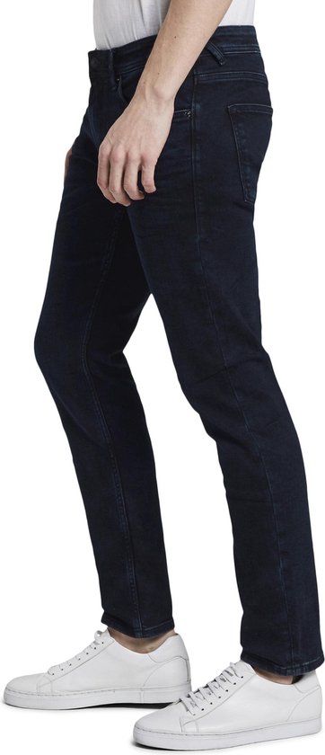 Een man draagt een donkerblauwe slim fit jeans.