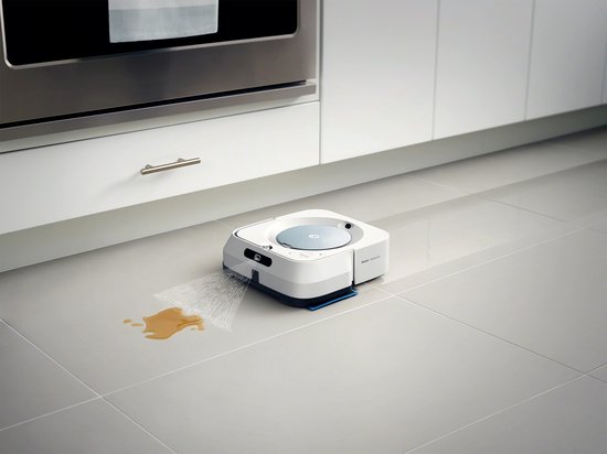 Witte robotdweilrobot op grijze tegels, reinigt een plas gemorste vloeistof.