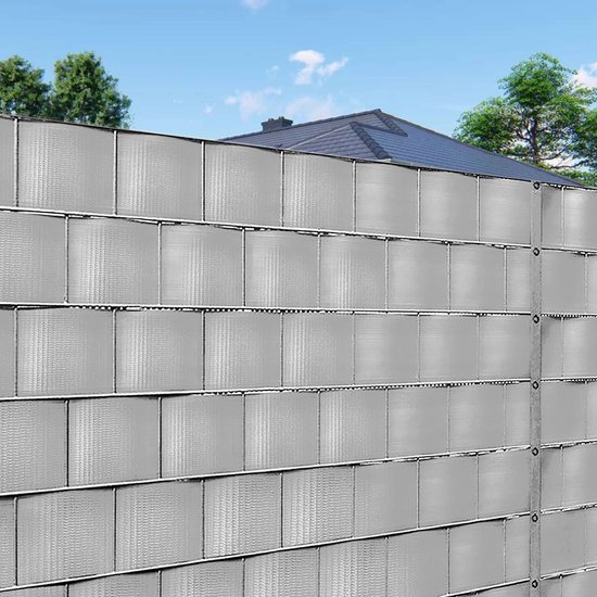 Grijze vlechtband met textuur, aangebracht op een hek, met een huis op de achtergrond.