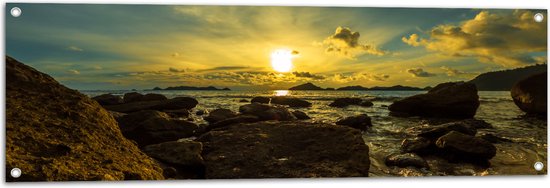 Tuinposter – Felkleurige Zonsondergang boven de Zee aan het Strand vol Rotsen - 120x40 cm Foto op Tuinposter (wanddecoratie voor buiten en binnen)