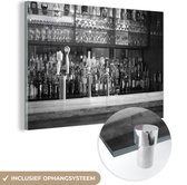 MuchoWow® Glasschilderij 150x100 cm - Schilderij acrylglas - Flessen drank en glazen op een bar - zwart wit - Foto op glas - Schilderijen