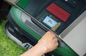 Hand die het scherm van een groene en zwarte robotmaaier bedient.