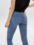 Close-up van de achterkant van een lichtblauwe skinny jeans, met een zwarte top.