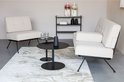 Twee beige bouclé fauteuils en een bank staan in een woonkamer op een vloerkleed.