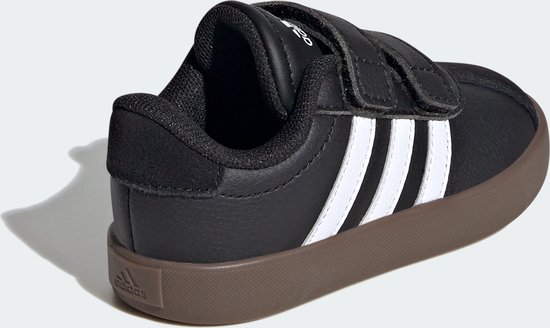 Zwarte Adidas sneaker met witte strepen, klittenband en bruine zool, gezien vanaf de achterkant.