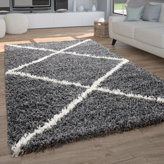 Tapis shaggy gris à motifs losanges blancs, posé sur un parquet dans un salon.