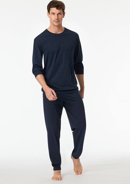 Man in donkerblauw pyjamaset met gestreept shirt en borstzakje.