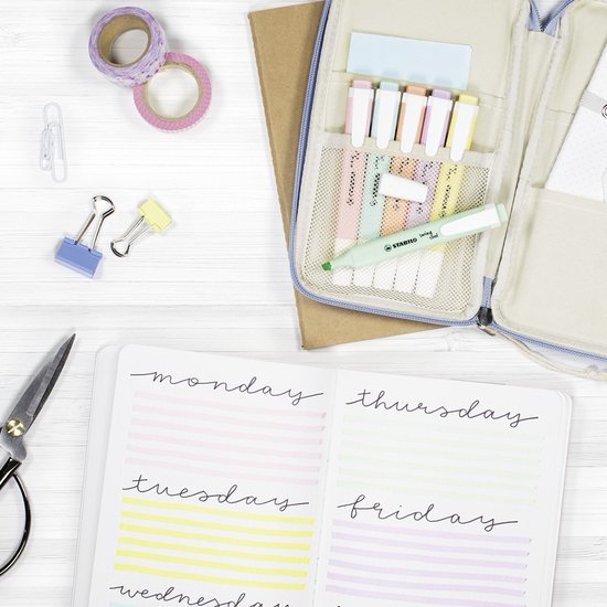 Bovenaanzicht van een opengeslagen bullet journal met dagen van de week en highlights, naast een etui met pastelkleurige markeerstiften.