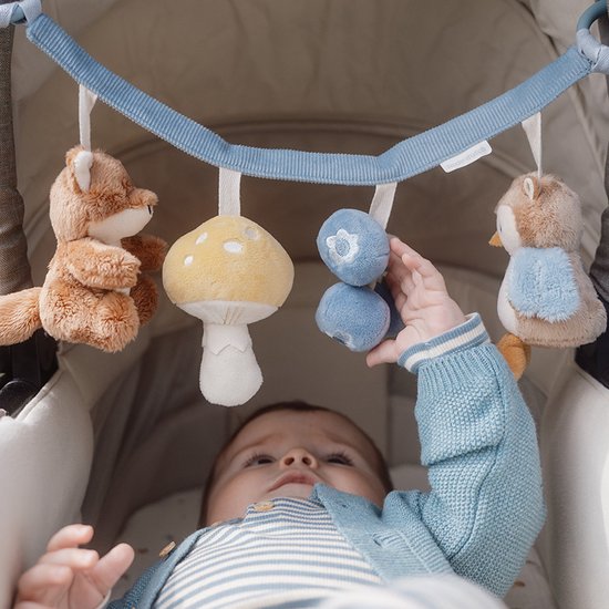 Baby speelt met kinderwagenhanger met vos, paddenstoel, bosbessen en uil.