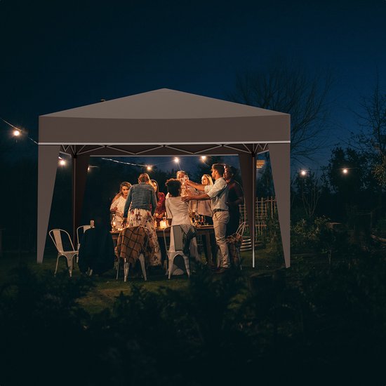 Bruine partytent met verlichting, opgesteld in een tuin tijdens een avondfeest.