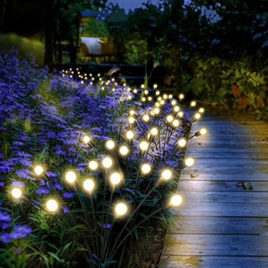 Jardin du soir éclairé par des lampes Boncy lucioles le long d'un chemin en bois et de fleurs violettes.