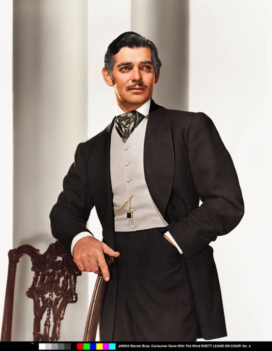 Rhett Butler in een formeel zwart pak met vest en grijze das, leunend op een stoel.