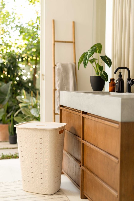 Beige wasmand met deksel en een ruitenpatroon naast een houten badmeubel.