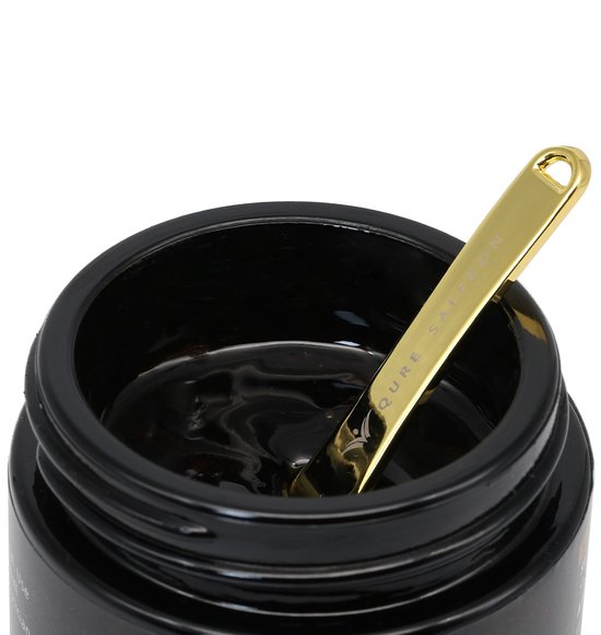 Binnenkant van een zwarte pot Shilajit Resin met een gouden lepel erin. De hars is donker en glanzend.