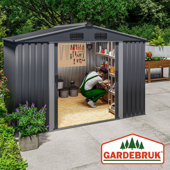 Een man in groene overall organiseert gereedschap in een donkergrijze metalen berging in de tuin.