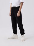 Jongen in een wit T-shirt en zwarte joggingbroek.