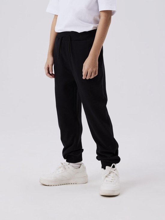 Jongen in een wit T-shirt en zwarte joggingbroek.