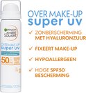 Witte spuitbus met Garnier Ambre Solaire logo, tekst 'OVER MAKE-UP super UV' en vinkjes voor bescherming.