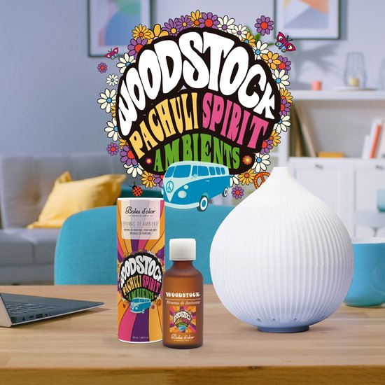 Een Woodstock Pachuli Spirit Ambiens geurverspreider en diffuser op een houten tafel met een laptop en een blauwe mok.