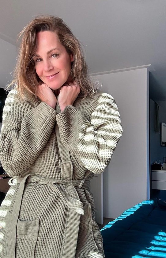 Vrouw in olijfgroene wafel badjas, met riem om en handen bij de nek.
