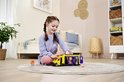 Meisje met vlechten speelt met een gele ambulance met open deuren en medische accessoires.