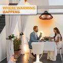 Zwarte hangende terrasverwarmer boven een gedekte tafel waar een koppel dineert.
