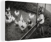 Canvas Schilderij Meisje die kippen voert in zwart-wit - 90x60 cm - Wanddecoratie
