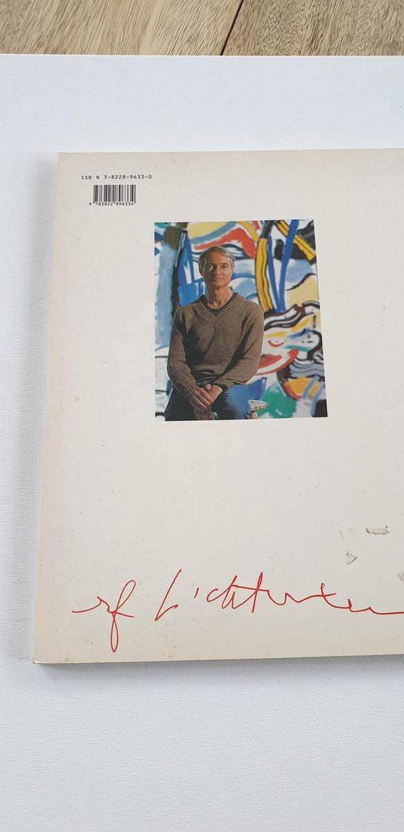Roy Lichtenstein zittend voor een van zijn schilderijen.