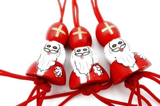 Drie houten gelukspoppetjes van Sinterklaas in rode kledij met witte baard en gouden kruis op mijter.
