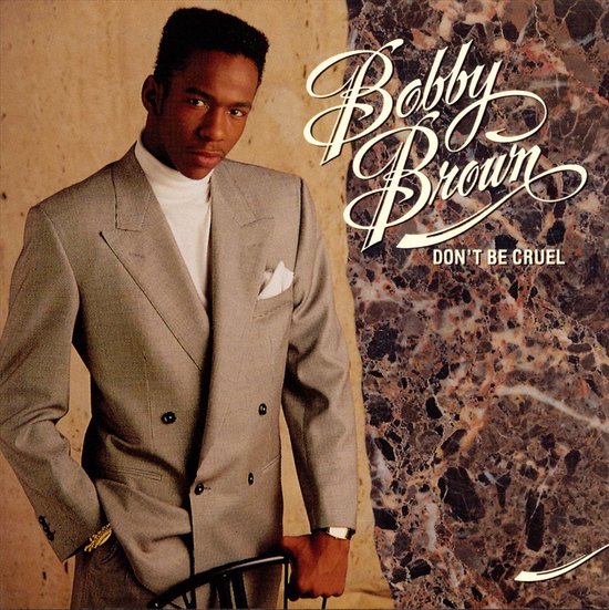 Bobby Brown draagt een lichtgrijs krijtstreeppak met een witte coltrui en zakdoek. Titel: DON'T BE CRUEL.