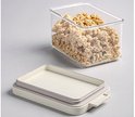 Une boîte de conservation transparente rectangulaire remplie de muesli, avec son couvercle beige détaché à côté.